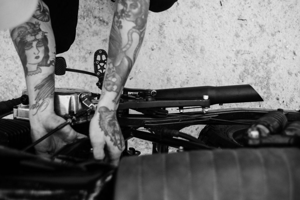 tattooed-biker-fixing-engine-of-motorcycle-4857741/